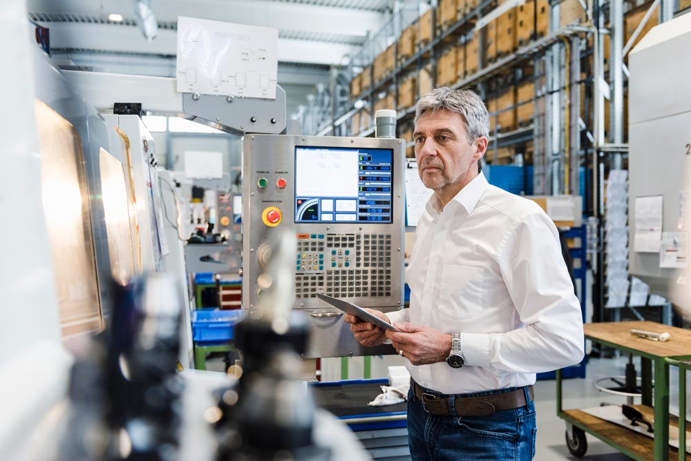 businessman on tablet in manufacturing plant